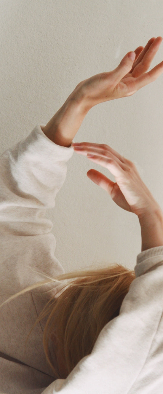 Delicate hands moving gracefully against a neutral wall background