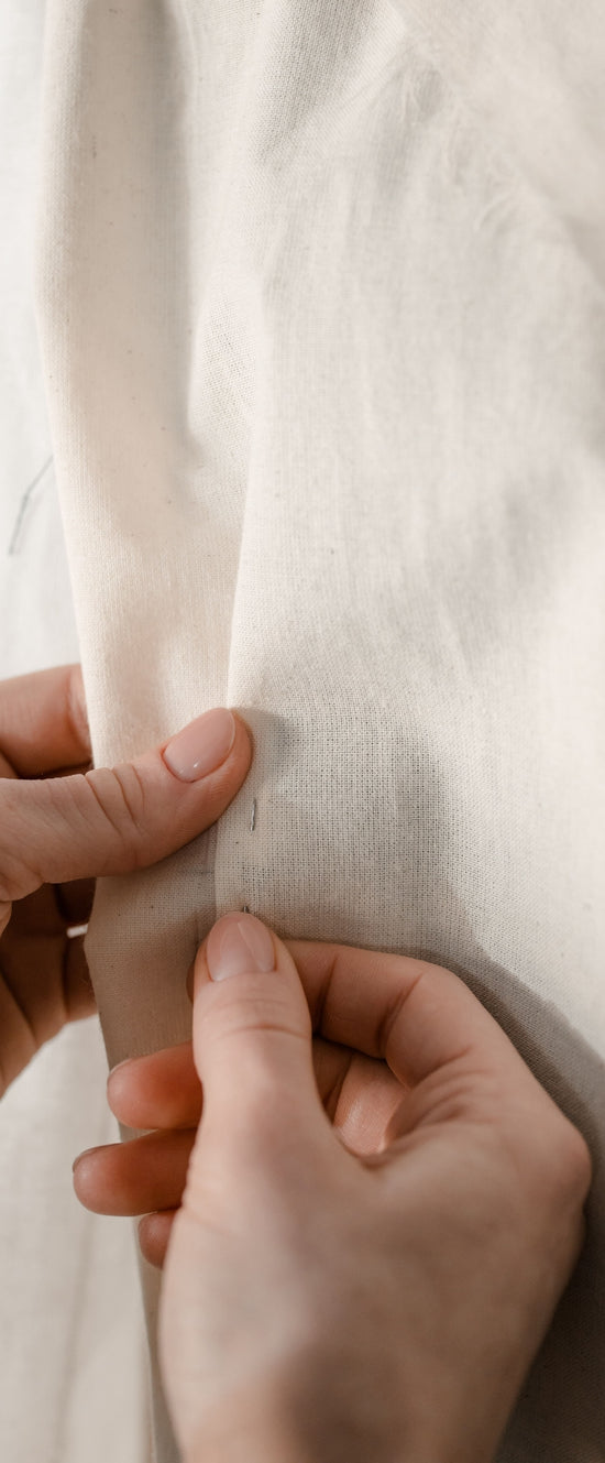 Hands pinching a soft white fabric close-up