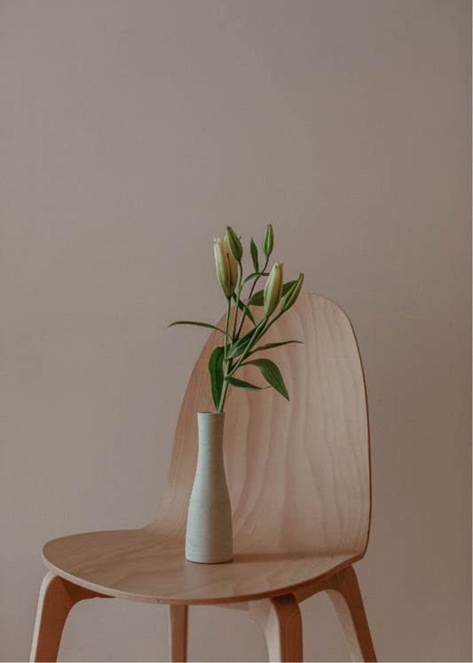Minimalist vase with flowers on a wooden chair