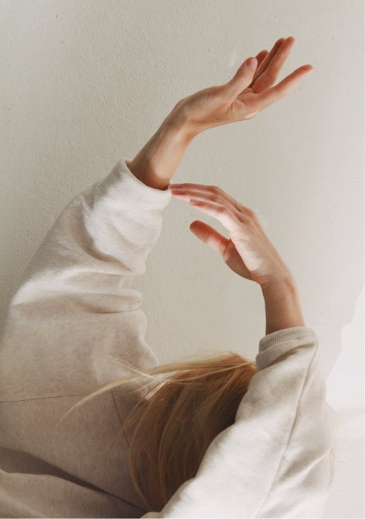 Soft focus of hands raised in graceful motion against a neutral background